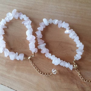 May include: Two delicate bracelets made with rose quartz chips and gold chain accents. The bracelets have a simple, elegant design and are perfect for everyday wear.