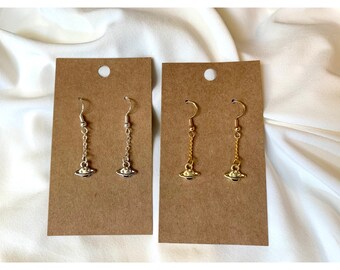 May include: Two pairs of dangle earrings with a small planet charm. One pair is silver and the other is gold.