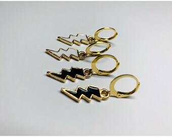 May include: Four gold hoop earrings with a lightning bolt charm. Two charms are black with white lightning bolts and two charms are white with black lightning bolts.