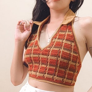May include: A brown and orange crocheted halter top with a plaid pattern. The top has a V-neck and a halter strap.