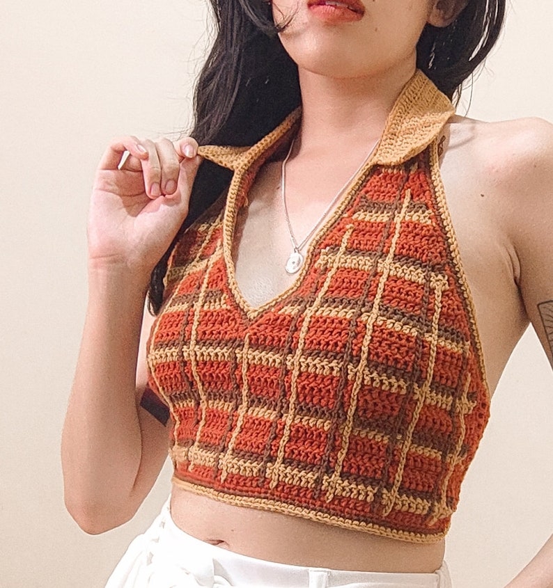 May include: A brown and orange crocheted halter top with a plaid pattern. The top has a V-neck and a halter strap.