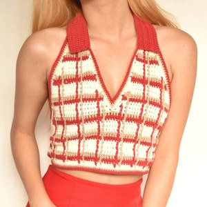 May include: A red and white crocheted halter top with a plaid pattern. The top has a V-neck and a halter strap.