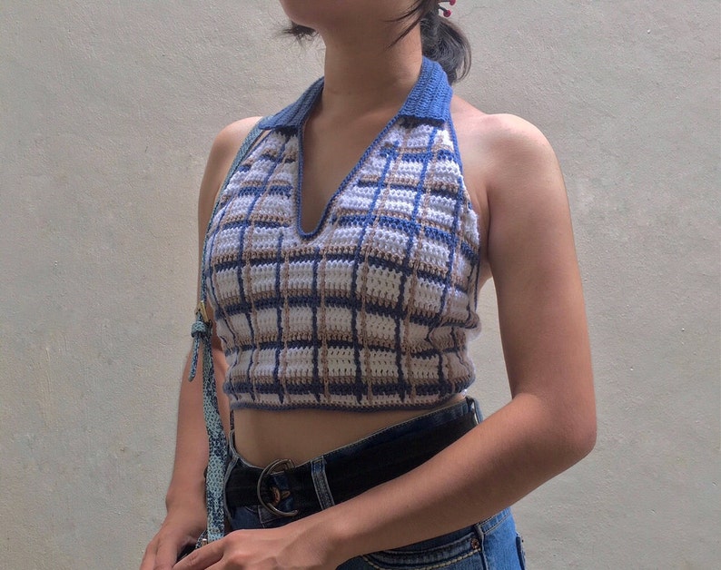 May include: A blue and brown plaid halter top with a v-neck and a crocheted design.