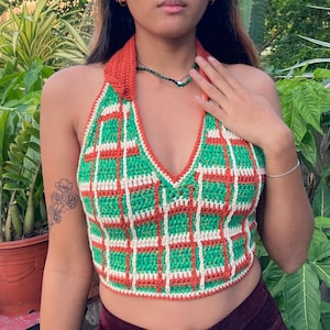 May include: A green and orange crocheted halter top with a white trim. The top has a plaid pattern and a deep V-neck.
