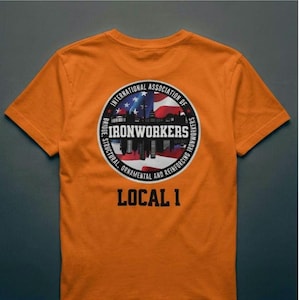 May include: Orange t-shirt with a circular emblem. The emblem features the text "INTERNATIONAL ASSOCIATION OF IRONWORKERS" and "LOCAL 1", a city skyline silhouette, and the American flag.