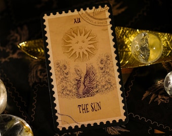 May include: A vintage tarot card with a black border and a gold background. The card depicts a sun with a face and a rooster with a crown. The card is labeled "XIX THE SUN".