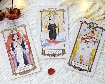 Pode incluir: Três cartas de tarô com bordas douradas e ilustrações. As cartas são "O Louco", "Temperança" e "Julgamento".