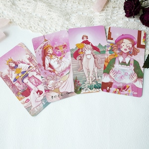 May include: Four tarot cards with pink backgrounds and illustrations of people and animals. The cards are labeled "Queen of Cups", "Knight of Cups", "Page of Cups", and "King of Cups".