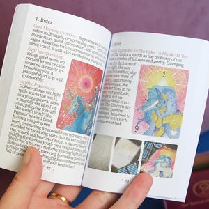 May include: An open guidebook with white pages featuring black printed text and colourful illustrations of a unicorn and a pegasus. The left page is titled 1. Rider and includes descriptive paragraphs. The right page shows a unicorn illustration.