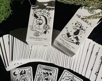 May include: A tarot card deck with black and white illustrations. The deck includes cards with various cartoon-style images and two white boxes with the text "BUZZING MOSQUITO TAROT" and "GOGO STUDIO".