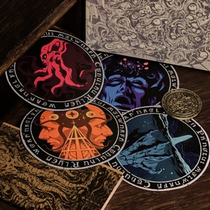 May include: Five round stickers with black and white text and colorful illustrations. The stickers feature a red octopus, a blue face, two faces with a third eye, and a blue and white creature.