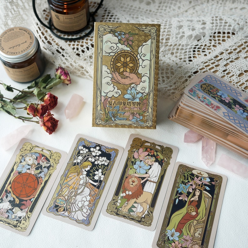 May include: A set of tarot cards with gold accents and illustrations. The cards feature a variety of images, including a lion, a woman with a crown, and a hand holding a sphere. The cards are titled "Retro Impression Tarot".