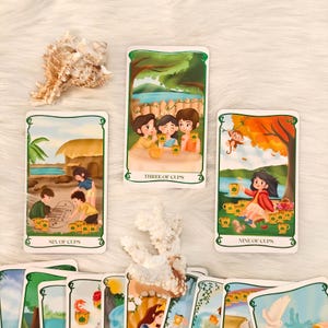 May include: A collection of tarot cards with illustrations. The cards feature images of people, landscapes, and objects. The cards are labeled with titles such as "Six of Cups," "Three of Cups," and "Nine of Cups."