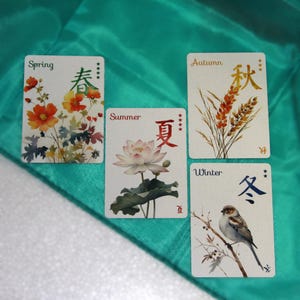 Pu&ograve; includere: Quattro carte rettangolari a tema stagionale. La carta della primavera presenta fiori arancioni, quella dell'estate un loto, quella dell'autunno grano e quella dell'inverno un uccello su un ramo. Ogni carta ha testo in inglese e caratteri asiatici.