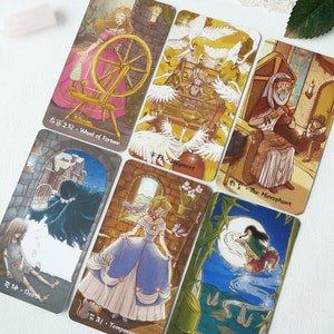 May include: A set of ten tarot cards with colorful illustrations and Chinese characters. The cards feature a variety of scenes, including a woman spinning a wheel, a woman in a cage, a man sitting on a throne, a woman in a blue dress, and a woman flying through the air.