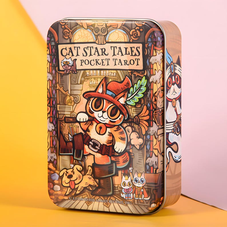 May include: A rectangular tin featuring a whimsical illustration of a cat character in a hat, holding a broom, with the text "CAT STAR TALES POCKET TAROT." The artwork is set against a stained-glass window background, with a dog and other cat characters.