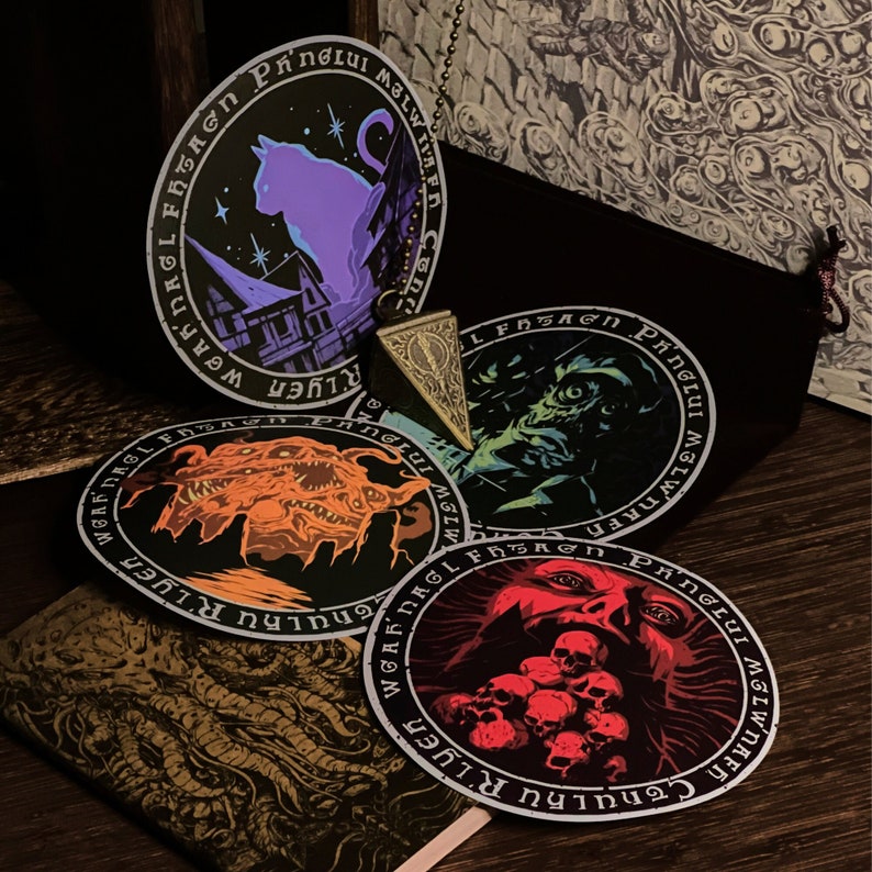 May include: Five round stickers with black borders and white text. The stickers feature different illustrations, including a cat, a creature with tentacles, a skull, and a creature with a large mouth. The text on the stickers includes the words "Cthulhu", "R'lyeh", "Ph'nglui", and "Mglw'nafh Cthulhu R'lyeh Wgah'nagl fhtagn".