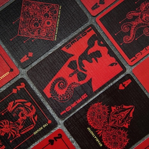 Puede incluir: Un juego de cartas con un esquema de color negro y rojo. Las cartas presentan ilustraciones de criaturas y el texto "JOKER" y "THE CASE OF CHARLES DEXTER WARD".