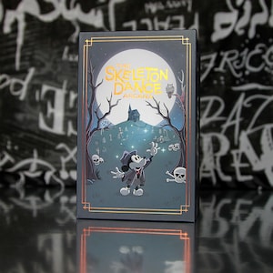 May include: A rectangular box featuring a spooky illustration with the text "THE SKELETON DANCE ARCANA." The artwork depicts a cartoon mouse character in a graveyard scene with a full moon, trees, and skulls. The box has gold trim.