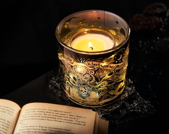 Könnte beinhalten: Ein beleuchtetes Teelicht in einem Glasvotiv mit goldfarbenen Illustrationen und Text. Das Design zeigt einen Totenkopf und Tentakel. Der Text auf dem Votiv lautet "R'lyeh wgah'nagl fhtagn".