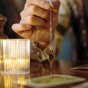Könnte beinhalten: Eine goldene Kettenkette mit einem tropfenförmigen Anhänger aus klarem Bernstein-Glas.