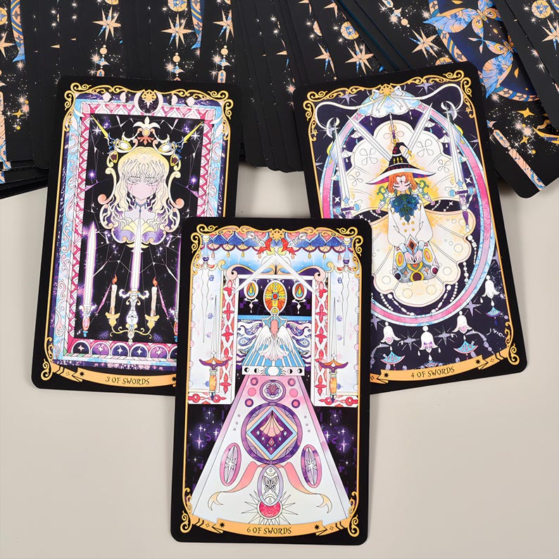 May include: A set of tarot cards featuring colorful illustrations with gold accents. The cards depict figures and symbols within ornate frames, with titles like "3 of Swords" and "4 of Swords" visible. The overall design has a mystical theme.