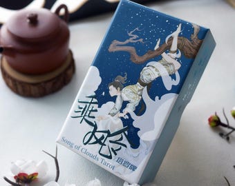 May include: A blue and white box with a depiction of a person flying through the clouds. The box has the text "Song of Clouds Tarot" and Chinese characters on it.