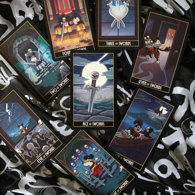 May include: A collection of tarot cards featuring illustrations with a cartoon theme. The cards display various scenes with swords, skulls, and other symbolic imagery. The cards are arranged on a black and white patterned surface.