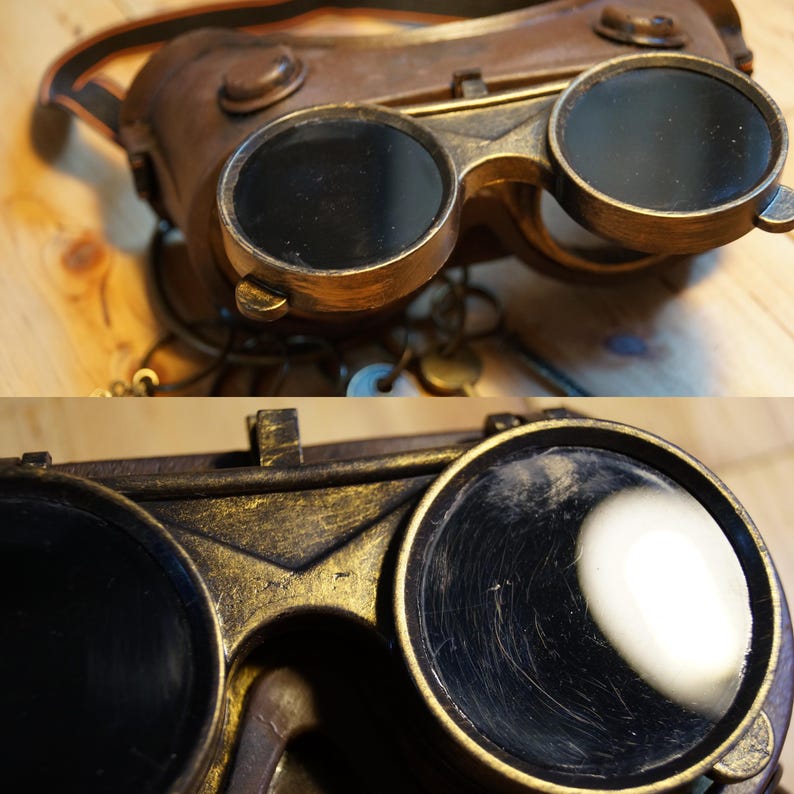 May include: A pair of steampunk-style goggles with round, dark lenses and a gold-colored metal frame. The goggles have a leather strap and are made of metal.