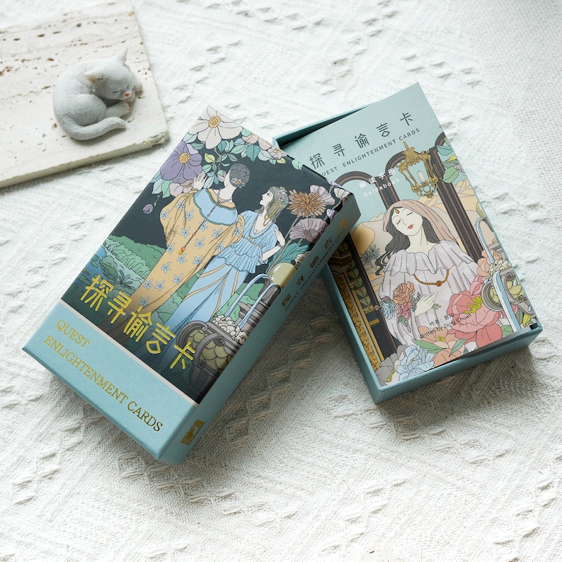 May include: A blue box with a gold border and the text "Quest Enlightenment Cards" on the front. The box contains a deck of cards with illustrations of people and flowers. The back of the box has the text "Quest Enlightenment Cards" in Chinese characters.