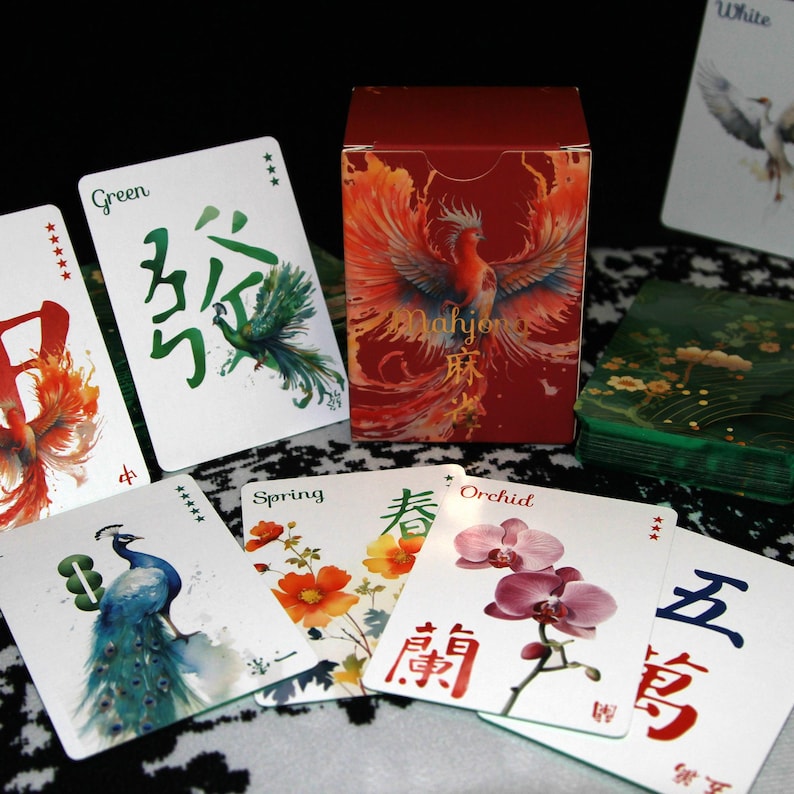 Pu&ograve; includere: Un set di Mahjong con una scatola rossa con un design a fenice e carte con illustrazioni floreali e di uccelli. Le carte presentano caratteri cinesi e parole inglesi come "Green", "Spring" e "Orchid".