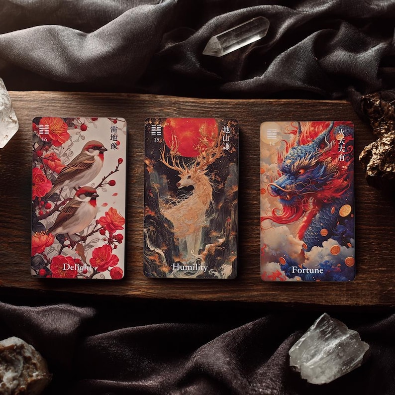 May include: Three rectangular oracle cards featuring artistic illustrations. The left card shows two birds among red flowers with the text Delight. The centre card depicts a deer with large antlers and a red sun labelled Humility. The right card shows a blue dragon with the text Fortune.