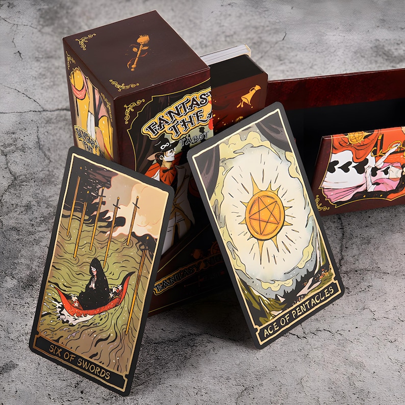 May include: A tarot card deck with a brown box featuring the text "FANTAS THE TAROT". Two cards are displayed: "Six of Swords" and "Ace of Pentacles". The cards have gold borders and detailed illustrations.
