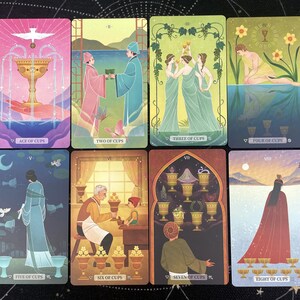 K&ouml;nnte beinhalten: Acht Tarotkarten mit farbenfrohen Illustrationen. Jede Karte zeigt eine andere Szene mit Figuren, Bechern und Symbolen. Die Karten sind mit r&ouml;mischen Ziffern und Titeln wie "Ace of Cups" und "Two of Cups" beschriftet. Die Karten liegen auf einer dunklen Oberfl&auml;che.