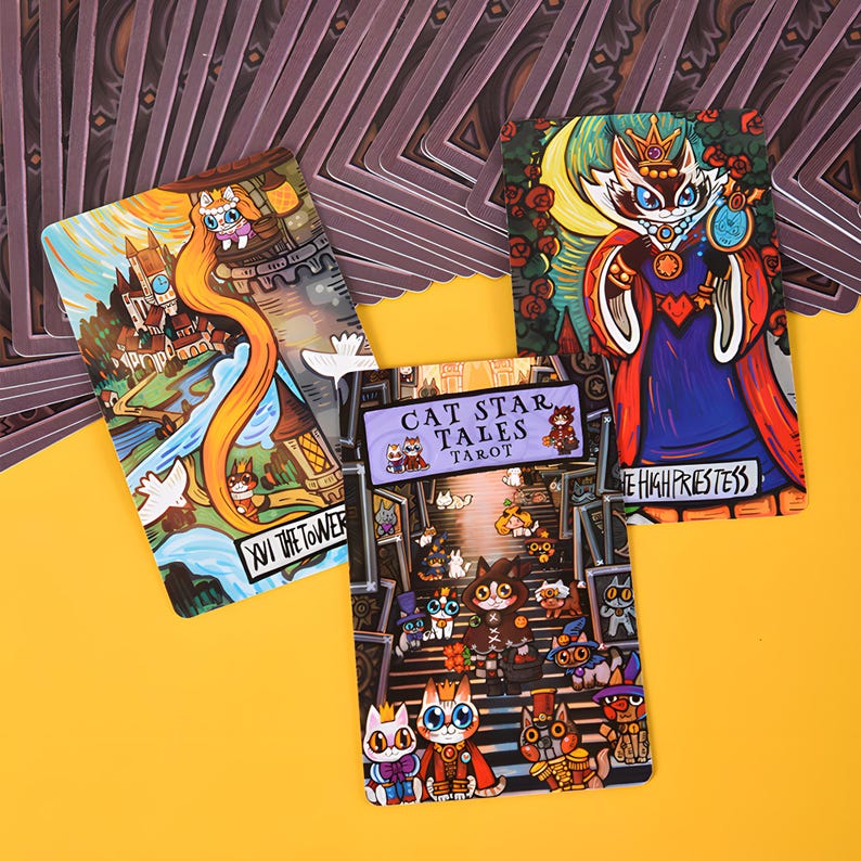 May include: A tarot card deck featuring whimsical cat illustrations. The cards showcase colorful artwork with titles like "The Tower" and "The High Priestess." The deck is titled "Cat Star Tales Tarot."