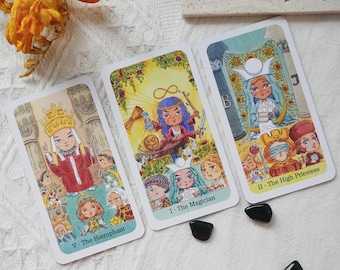 May include: Three tarot cards with colorful illustrations and the titles "V. The Hierophant", "I. The Magician", and "II. The High Priestess". The cards feature cartoon-style figures and symbols. Black stones are scattered near the cards.