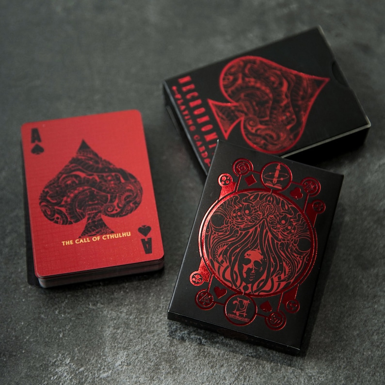 Puede incluir: Tres cartas de juego con fondos negros y acentos de l&aacute;mina roja. Las cartas presentan un dise&ntilde;o de picas con detalles intrincados. El texto en las cartas dice "The Call of Cthulhu" y "Playing Cards".