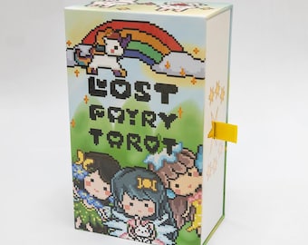Puede incluir: Una caja para una baraja de tarot Lost Fairy. La caja es azul, amarilla y verde con un arcoíris y un unicornio en la parte delantera. El texto "LOST FAIRY TAROT" está en letras pixeladas negras.