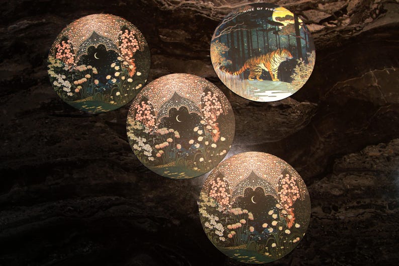 May include: Four round decorative art pieces. Three feature a night scene with a crescent moon, flowers, and an arched structure. The fourth depicts a tiger in a forest with the text "NINE OF FIRE".