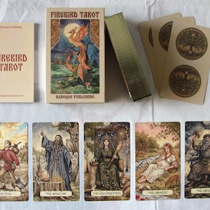 Könnte beinhalten: Ein Firebird Tarot-Deck von Baroque Publishing mit einer Schachtel mit Phönix-Illustration, einem Begleitbuch und Karten mit detaillierten Motiven wie Der Narr, Der Magier, Die Hohepriesterin, Die Herrscherin und Der Herrscher.