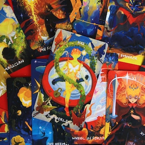 Puede incluir: Un conjunto de cartas de tarot coloridas con diversas ilustraciones y texto. Las cartas presentan imágenes de figuras, símbolos y elementos celestiales. Algunas cartas tienen texto como "El Mago", "La Emperatriz" y "El Mundo".