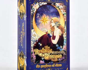 May include: A tarot card box with a dark blue background and gold accents. The box features an illustration of a woman on a crescent moon, with the text "The Radiant Essence tarot cards" and "the prophecy of chaos".