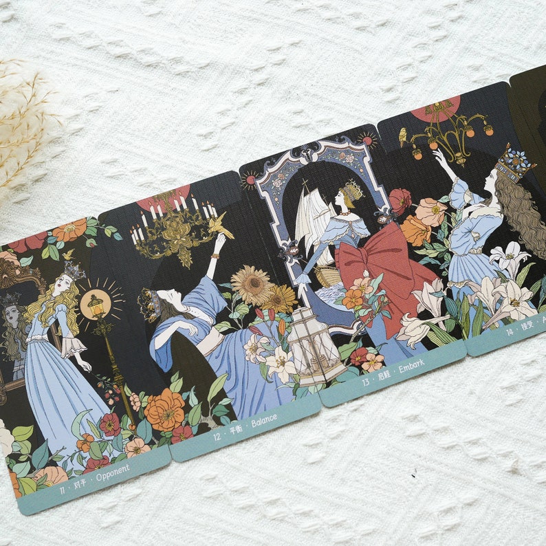 May include: A set of tarot cards with illustrations of women in various poses. The cards are numbered and have text in a foreign language. The cards are on a white surface.