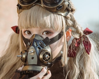 May include: A woman wearing a steampunk-style gas mask with a gold and black finish. The mask has a gear design and spikes. She is also wearing goggles with a gold frame and black lenses.