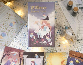 Puede incluir: Una baraja de cartas de tarot Bohme con un fondo morado y una ilustración caprichosa de una mujer con un sombrero de bruja sosteniendo una varita. El texto "波姫塔羅牌 Bohme Tarot" está impreso en la caja.