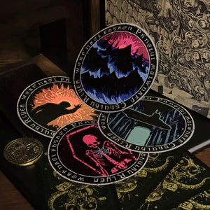 May include: Four round stickers with black borders and white text. The text reads "WGAFDAGLFBSAGN PINGLUI MSLWNAFF Cthulhu RLYER" and "WOAR THULKU RLYER" and "WGAF DAGLI FBSAgn Ping HULKURIYER" and "W INTguud M I Z W NA FH CTHULHU RLYER". The stickers have different colorful images inside the borders. One sticker has a dark silhouette of a creature with a bright orange background. Another sticker has a dark silhouette of a creature with a blue and purple background. Another sticker has a submarine in front of a blue and green background. The last sticker has a skeleton with a pink and purple background.