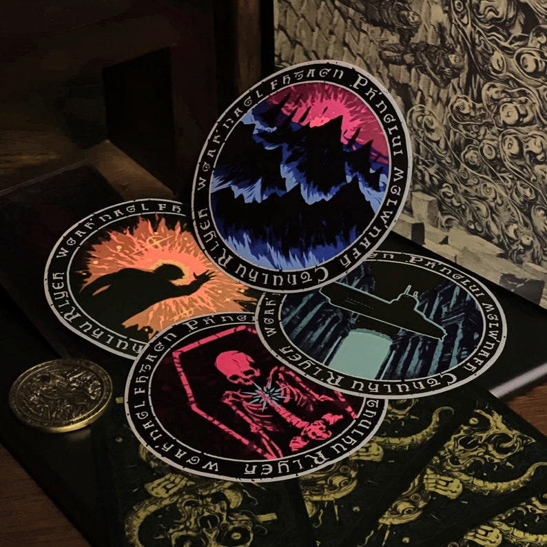 May include: Four round stickers with black borders and white text. The text reads "WGAFDAGLFBSAGN PINGLUI MSLWNAFF Cthulhu RLYER" and "WOAR THULKU RLYER" and "WGAF DAGLI FBSAgn Ping HULKURIYER" and "W INTguud M I Z W NA FH CTHULHU RLYER". The stickers have different colorful images inside the borders. One sticker has a dark silhouette of a creature with a bright orange background. Another sticker has a dark silhouette of a creature with a blue and purple background. Another sticker has a submarine in front of a blue and green background. The last sticker has a skeleton with a pink and purple background.
