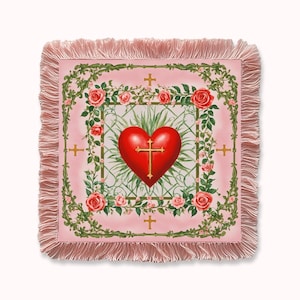 May include: A square pink throw blanket featuring a red heart and gold cross design. The heart is central, surrounded by a floral border with roses and gold crosses. The blanket has a pink fringe.
