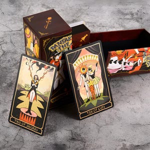 May include: A tarot card deck with a burgundy box featuring the text "Fantasy Tarot". The cards display colorful illustrations, including "Two of Swords" and "Ten of Cups". The box and cards have a vintage aesthetic.