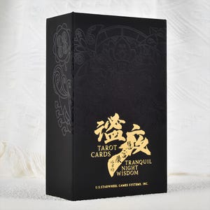 Könnte beinhalten: Eine schwarze Tarotkartenbox mit goldfarbenen Buchstaben und geprägten Designs. Auf der Box steht "Tarot Cards" und "Tranquil Night Wisdom" in englischer und chinesischer Schrift. Die Box ist rechteckig und steht aufrecht.
